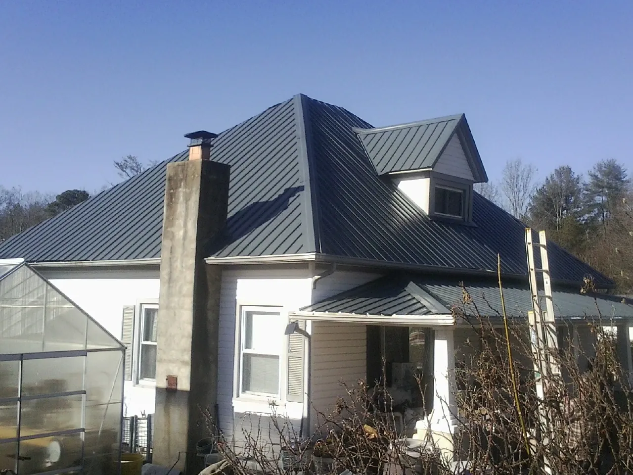 Dark blue standing seam metal roof on a white farmhouse with dormer — Slate & Tile Roof Repair by Roofing Brothers in Rollinsford