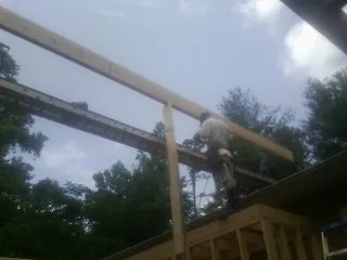 Carpenter setting a ridge beam over a new addition frame — Ice Dam Removal by Roofing Brothers in Rollinsford