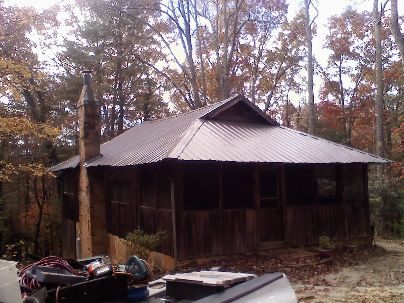Brown metal hip roof on an old cabin with a stone chimney in Rollinsford