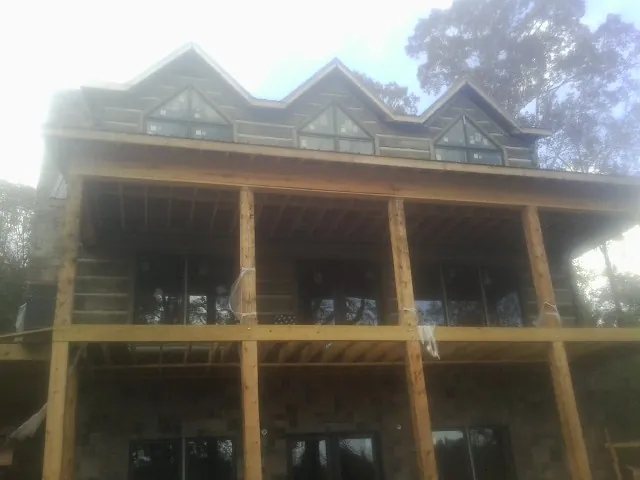 Dormers and porch framing on a large log home under construction — Roof Coating work by our crew in Rollinsford