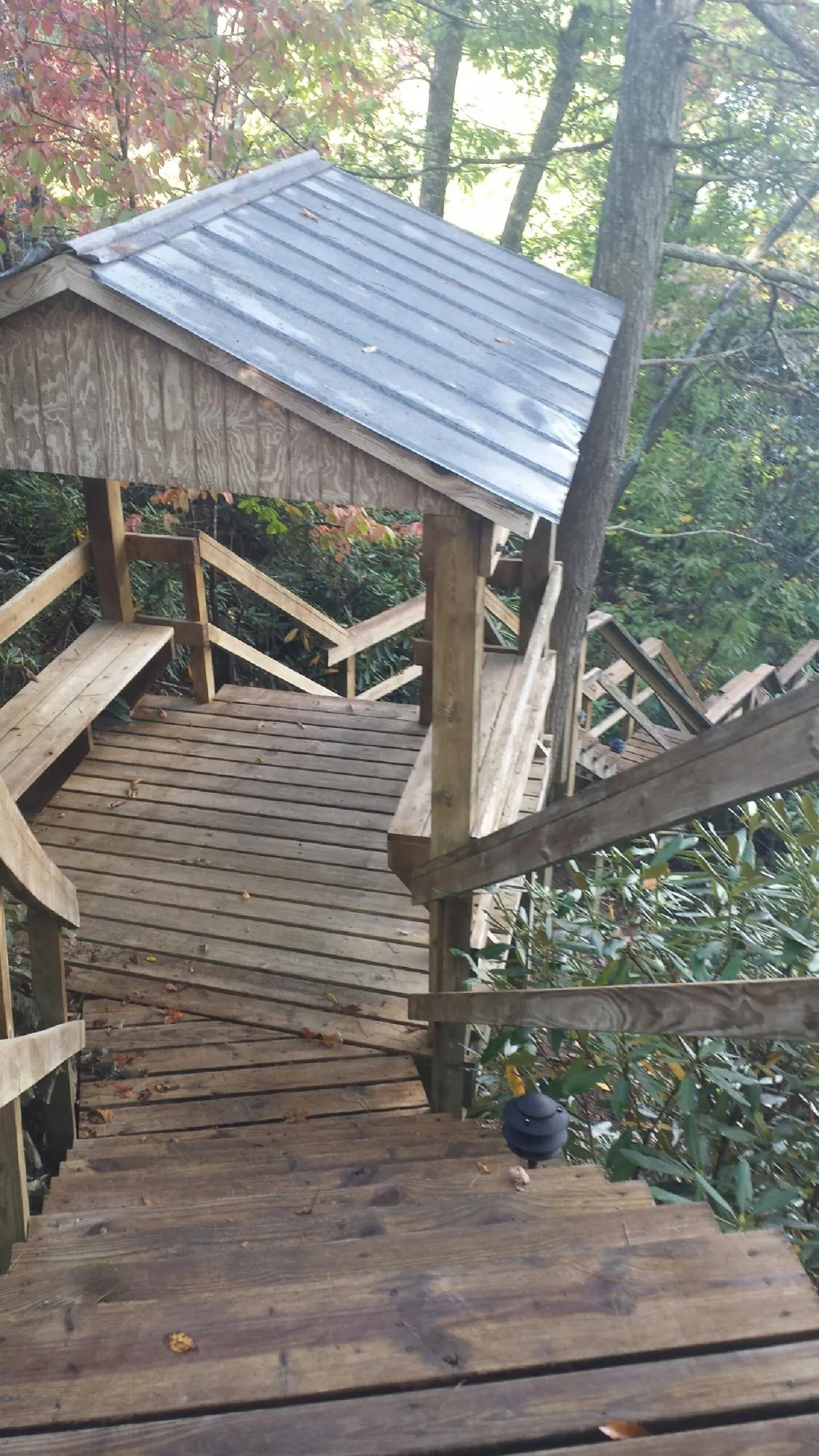 Metal roofed shelter over wooden steps on a wooded walkway — Skylight Repair & Installation work by our crew in Rollinsford