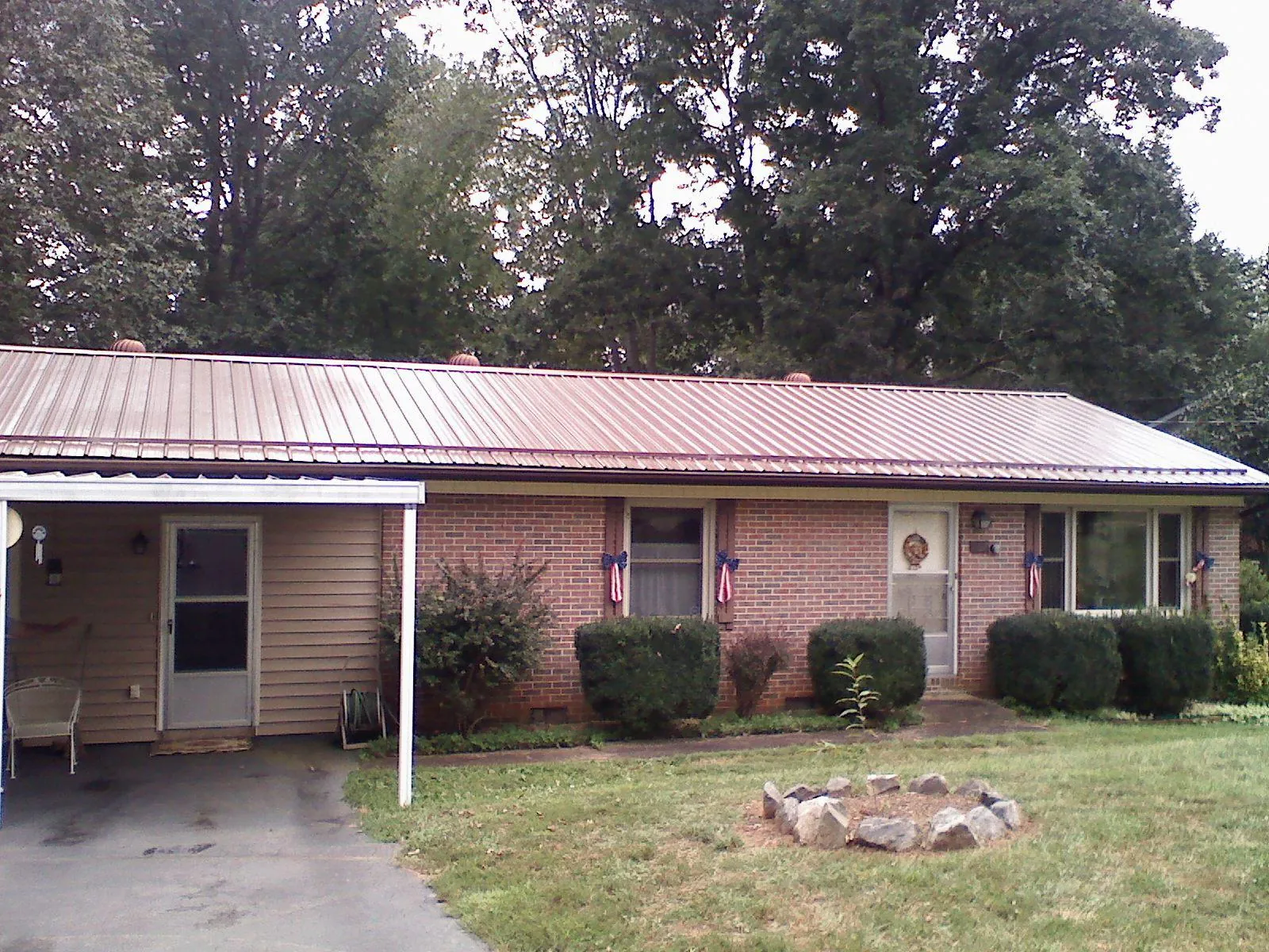 Bronze metal roof and carport on a brick ranch home — Roof Repair work by our crew in Rollinsford