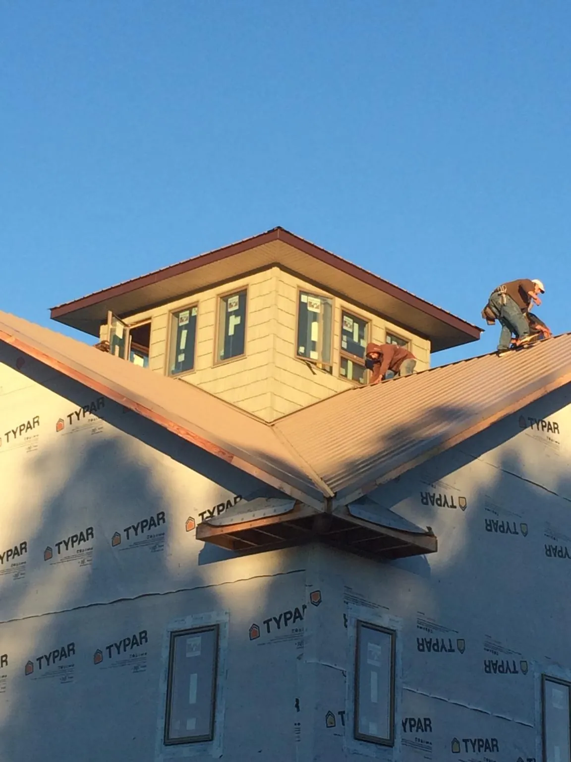 Roofers working around a rooftop cupola on a new metal roof at sunset — Roof Waterproofing in Rollinsford by Roofing Brothers